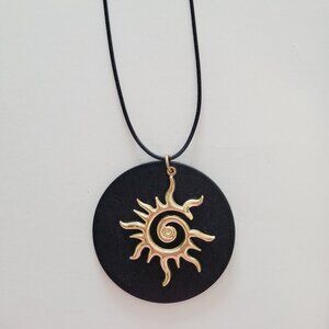 Collar de sol dorado sobre madera negra artesanal